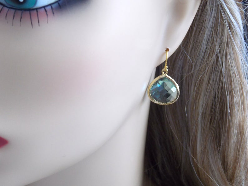 May include: Gold teardrop earrings with a blue-green gemstone.