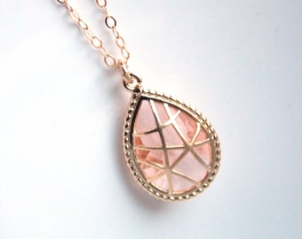 May include: A delicate gold chain necklace with a teardrop-shaped pendant featuring a pink crystal encased in a gold wire frame.