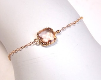 May include: A delicate gold chain bracelet with a single, clear, faceted gemstone pendant.