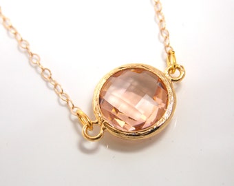 May include: A gold chain necklace with a single, large, round, light pink gemstone pendant.