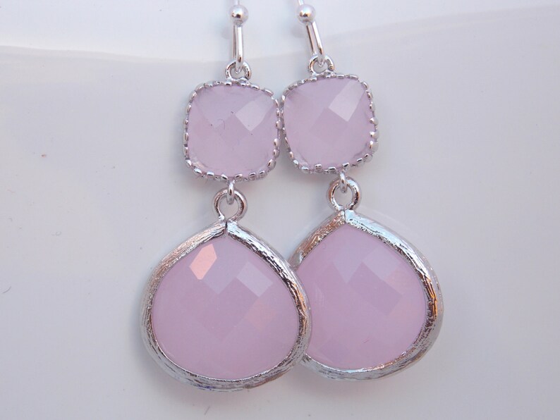 May include: A pair of silver dangle earrings with two pink faceted glass stones on each earring.