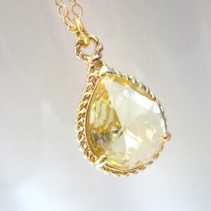May include: A gold necklace with a teardrop-shaped yellow crystal pendant.