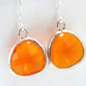 May include: A pair of silver dangle earrings with orange faceted gemstone drops.