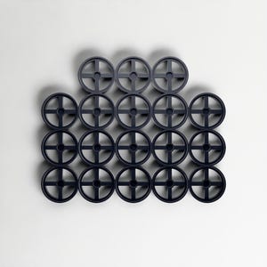 May include: A collection of twenty dark blue circular objects, each featuring a cross-shaped design at the centre. They are arranged in a grid pattern against a white backdrop. The objects appear to be made of plastic, and are evenly spaced.