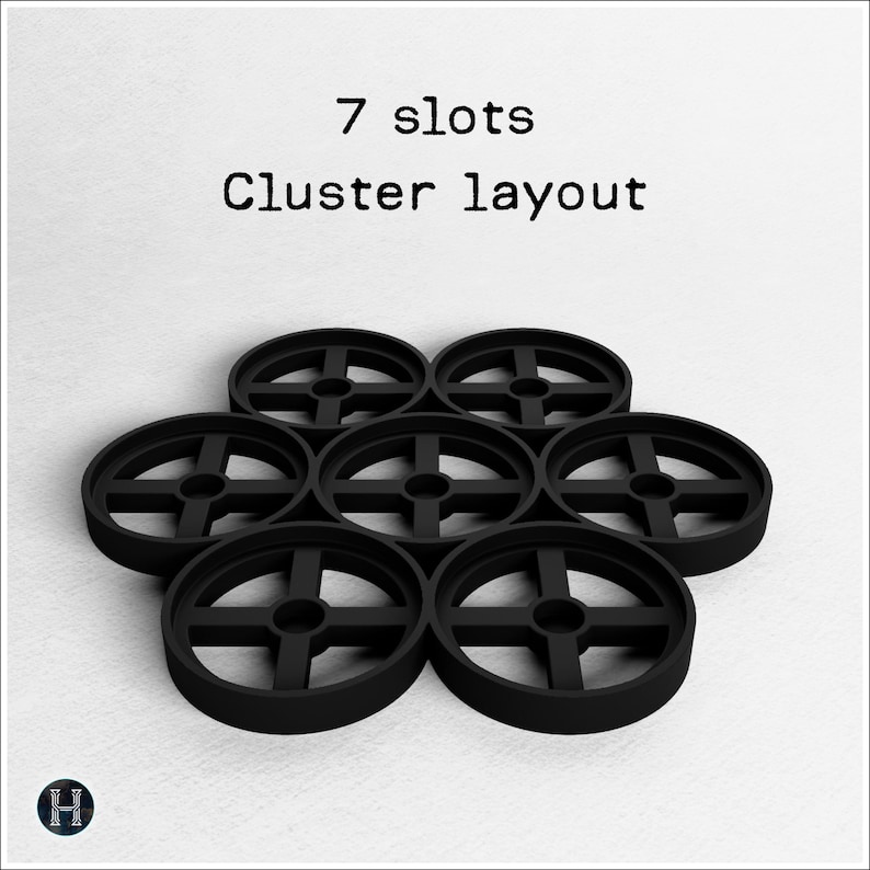 May include: Seven black circular objects arranged in a cluster layout. Each object has a cross-shaped design in the center. The text "7 slots Cluster layout" is above the objects.