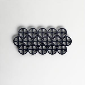 Pode incluir: Uma cole&ccedil;&atilde;o de dezesseis objetos circulares azul escuro com um design em forma de cruz no centro, dispostos em um padr&atilde;o de grade contra um fundo branco. Os objetos parecem ser feitos de pl&aacute;stico ou material semelhante. Di&acirc;metro de cerca de 5 cm.