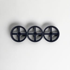 Pode incluir: Tr&ecirc;s decora&ccedil;&otilde;es de parede circulares azul marinho com um design em forma de cruz dentro de cada c&iacute;rculo. Os objetos est&atilde;o espa&ccedil;ados uniformemente e dispostos horizontalmente contra um fundo branco, projetando uma sombra sutil.