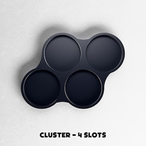 May include: A dark navy blue cluster with four circular slots. The slots are arranged in a unique pattern, with three slots clustered together and one separate. The text "CLUSTER - 4 SLOTS" is at the bottom of the image.
