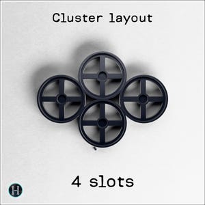 May include: A cluster of four dark gray, circular objects with cross-shaped designs, arranged in a square formation. The text "Cluster layout" and "4 slots" are displayed above and below the objects, respectively.