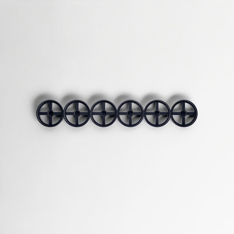 Pode incluir: Seis objetos circulares azuis escuros com um design em forma de cruz no centro, dispostos horizontalmente sobre um fundo branco. Os objetos t&ecirc;m uma apar&ecirc;ncia semelhante a rodas, com um cubo central e raios.