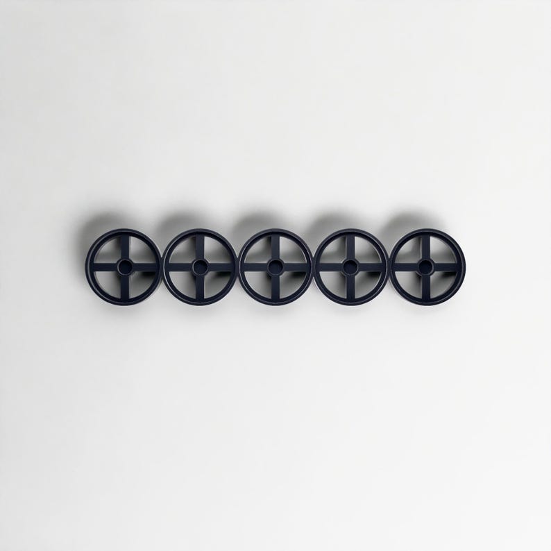 Pode incluir: Cinco ganchos de parede circulares azul marinho dispostos horizontalmente. Cada gancho apresenta um design em forma de cruz dentro do c&iacute;rculo. Os ganchos s&atilde;o montados em um fundo branco liso, criando uma est&eacute;tica minimalista.