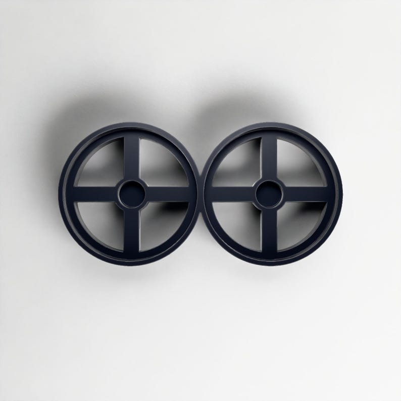 Pode incluir: Dois objetos circulares azul marinho com um design em forma de cruz no interior. Os objetos s&atilde;o sim&eacute;tricos e parecem ser feitos de um material s&oacute;lido. O fundo &eacute; branco liso.