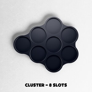 May include: A dark navy blue cluster-shaped organizer with eight circular slots. The text "CLUSTER - 8 SLOTS" is printed in bold, black letters at the bottom of the image. The organizer is set against a white background.