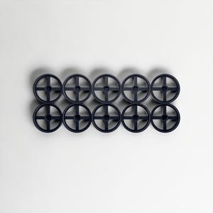 May include: Ten dark blue, circular objects with a cross-shaped design in the centre, arranged in two rows of five. The objects are evenly spaced against a white background, creating a symmetrical pattern.