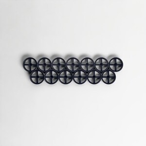 Pode incluir: Um cabide de parede azul marinho escuro com uma s&eacute;rie de ganchos circulares em forma de roda. Os ganchos est&atilde;o dispostos horizontalmente, criando um design moderno e minimalista. O cabide &eacute; feito de um material s&oacute;lido e est&aacute; sobre um fundo branco liso.