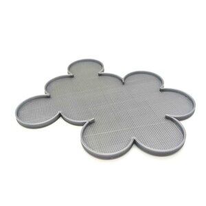May include: A gray, cloud-shaped trivet with a textured surface. The trivet has a series of rounded lobes, resembling a stylized flower or cloud. The trivet is made of a solid material and is designed to protect surfaces from heat.