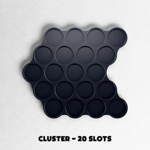 May include: A dark navy blue cluster tray with 20 circular slots. The tray has a unique, curved shape and is designed to hold small items. The text "CLUSTER - 20 SLOTS" is printed in black at the bottom of the image.