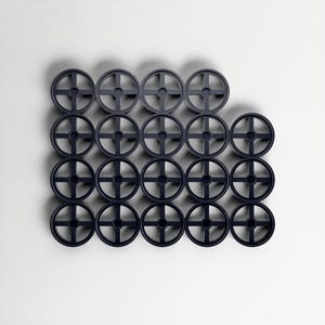 May include: A collection of twenty-one dark navy blue, circular, wheel-shaped objects. Each wheel features a cross-shaped design at its centre. The objects are arranged on a white background, forming a geometric pattern.