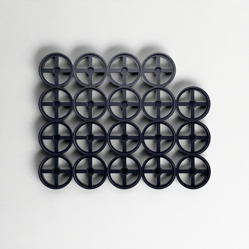 May include: A collection of twenty-one dark navy blue, circular, wheel-shaped objects. Each wheel features a cross-shaped design at its centre. The objects are arranged on a white background, forming a geometric pattern.