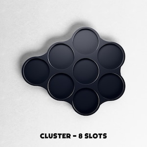 May include: A dark navy blue cluster-shaped organizer with eight circular slots. The text "CLUSTER - 8 SLOTS" is printed in bold, black letters at the bottom of the image. The organizer is set against a white background.