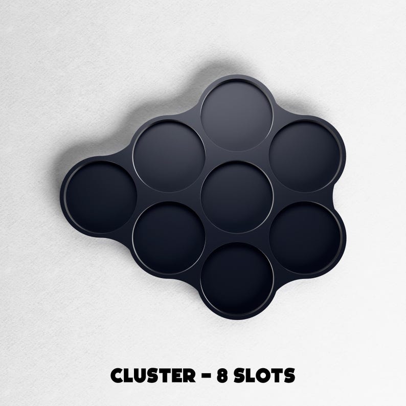 May include: A dark navy blue cluster-shaped organizer with eight circular slots. The text "CLUSTER - 8 SLOTS" is printed in bold, black letters at the bottom of the image. The organizer is set against a white background.