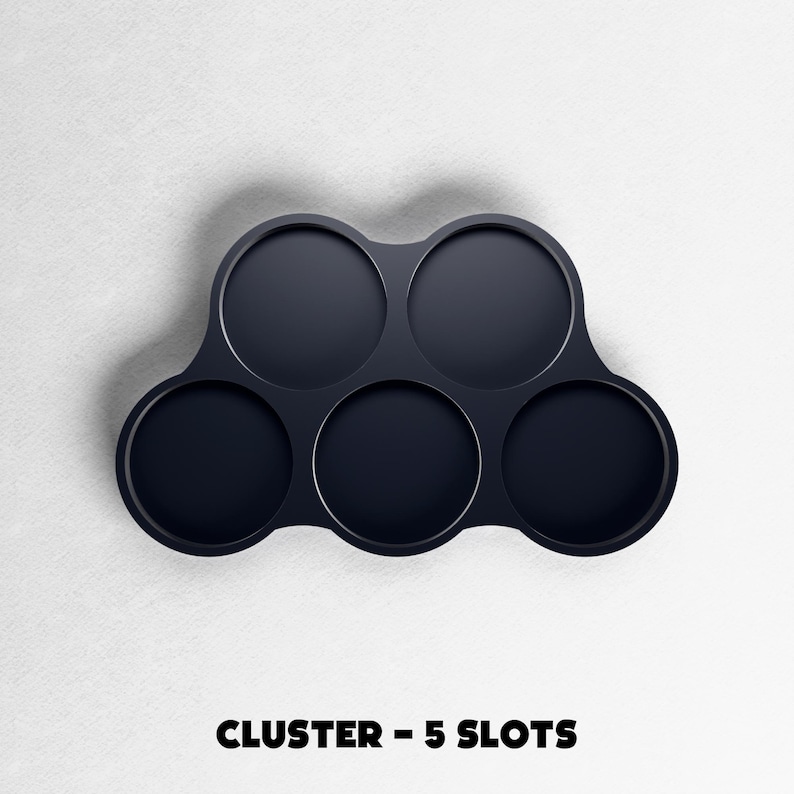 May include: A dark navy blue cluster with five circular slots. The product is designed to hold multiple items. The text "CLUSTER - 5 SLOTS" is printed in bold, black letters at the bottom of the image.