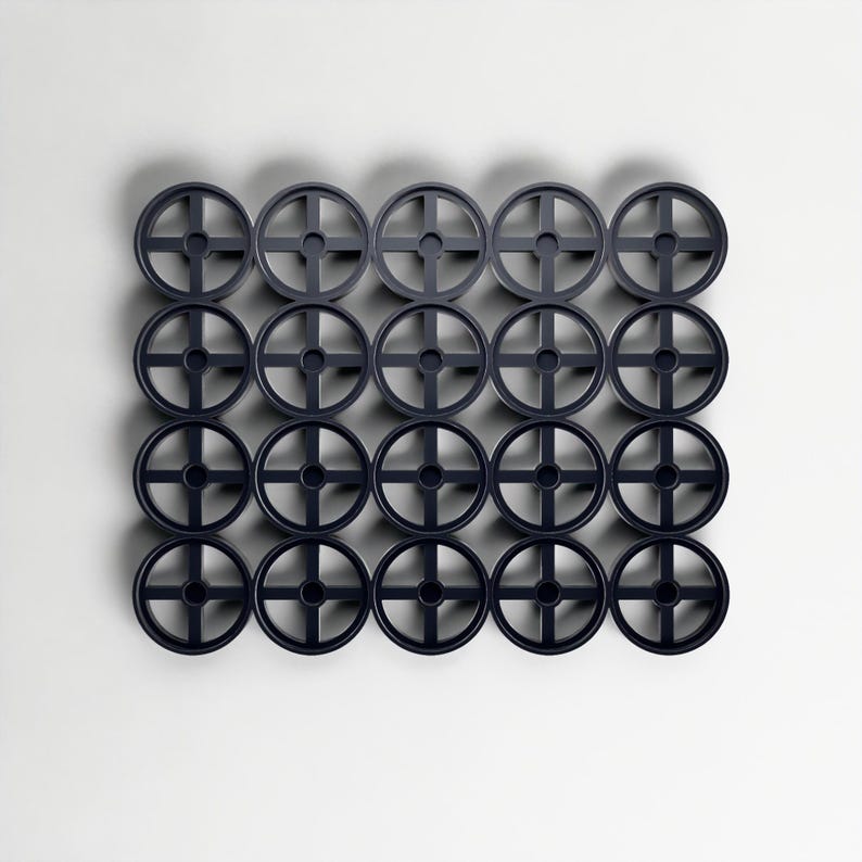 May include: Twenty-four dark blue circular objects, each with a cross-shaped design, arranged in a grid against a white backdrop. The objects are evenly spaced. They appear to be made of plastic. The objects are approximately 10 cm in diameter.