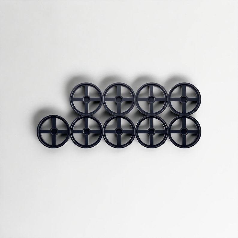 May include: Nine dark navy blue, wheel-shaped objects arranged in a grid pattern. Each wheel has a central hub with four spokes extending outwards. The objects are evenly spaced against a white background, casting subtle shadows.