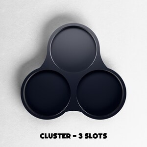 May include: A dark navy blue cluster with three circular slots. The object is made of a smooth material and is set against a white background. The text "CLUSTER - 3 SLOTS" is displayed at the bottom of the image.