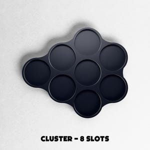 May include: A dark navy blue cluster-shaped organizer with eight circular slots. The text "CLUSTER - 8 SLOTS" is printed in bold, black letters at the bottom of the image. The organizer is set against a white background.