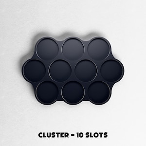May include: A dark navy blue cluster tray with ten circular slots. The tray is on a white background. The text "CLUSTER - 10 SLOTS" is printed in black at the bottom of the image.