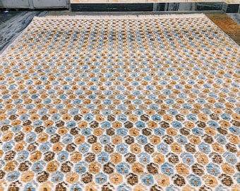 May include: A rectangular area rug featuring a repeating hexagonal pattern in shades of light blue, golden yellow, and dark brown on a cream-coloured background. The rug has a short pile texture and includes a fringe detail along the top edge.