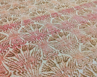 May include: A woven textile featuring a repeating fan-shaped pattern in shades of coral, peach, and muted brown against a cream-coloured background. The fabric displays a textured surface with a dense, intricate weave that creates a consistent design.