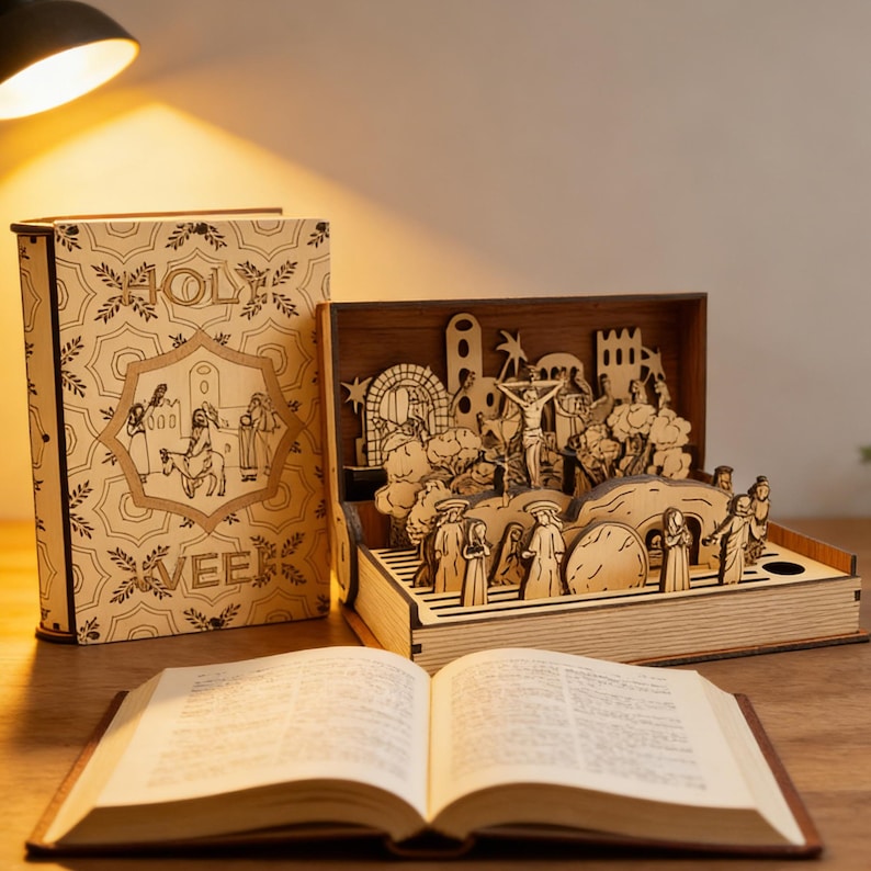 K&ouml;nnte beinhalten: Ein lasergeschnittenes Holz-Diorama, das eine religi&ouml;se Szene darstellt, pr&auml;sentiert in einer offenen, buchf&ouml;rmigen Box. Die Box zeigt eine detaillierte dreidimensionale Szene mit Figuren und architektonischen Elementen. Ein offenes Buch liegt davor.