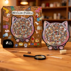 Puede incluir: Un rompecabezas de madera con forma de gato de 135 piezas, con una colorida ilustraci&oacute;n de numerosos gatos. El rompecabezas se muestra junto a su caja, que tambi&eacute;n tiene la imagen del rompecabezas y las palabras "Wooden Puzzle". Una lupa y un cepillo est&aacute;n sobre la mesa.