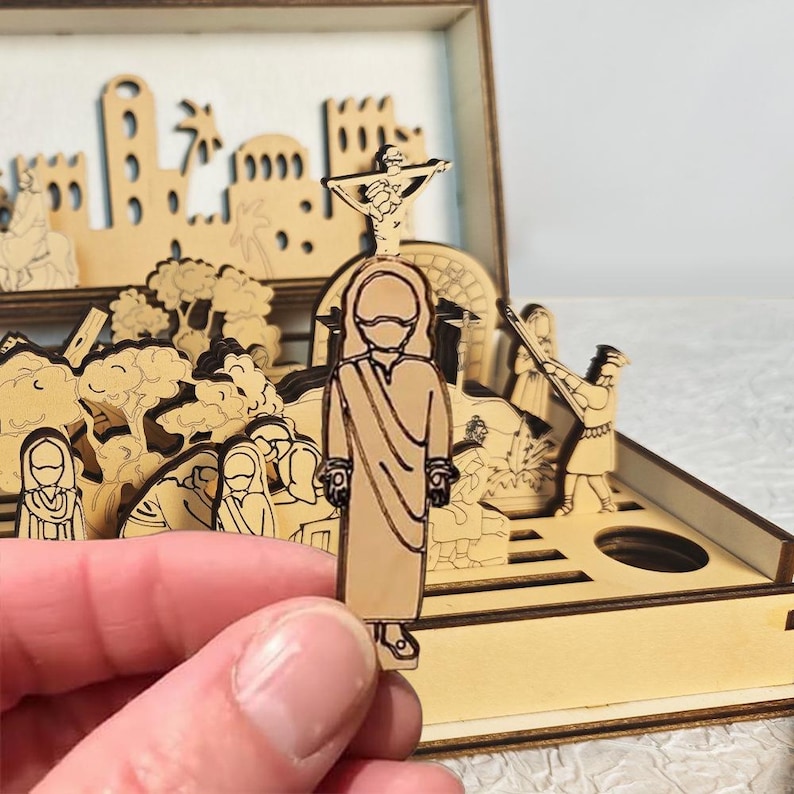 K&ouml;nnte beinhalten: Ein Holz-Diorama, das eine religi&ouml;se Szene darstellt, mit Figuren, Geb&auml;uden und einem Kreuz. Das Diorama besteht aus hellem Holz mit aufwendigen Ausschnitten. Eine Figur wird vor dem Diorama gehalten.