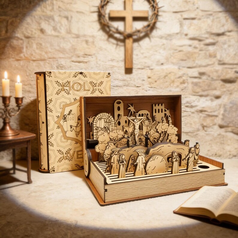 K&ouml;nnte beinhalten: Ein lasergeschnittenes Holz-Diorama, das eine religi&ouml;se Szene darstellt, mit Figuren, B&auml;umen und Strukturen in einer Box. Ein Buch mit dem Wort "HOLY" ist sichtbar. Ein Kreuz und Kerzen sind im Hintergrund.