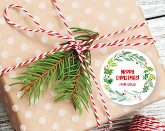 May include: A round Christmas gift tag with a watercolor wreath of green leaves, red berries, and the text "Merry Christmas! From Hadley".