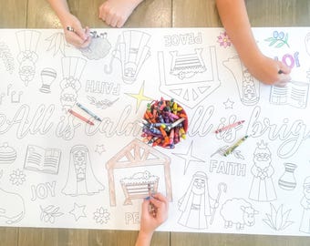 May include: A large white paper roll with a Christmas nativity scene design. The paper is decorated with images of stars, angels, shepherds, and the words "Peace", "Faith", and "Joy". The paper is being colored in by three people using crayons.