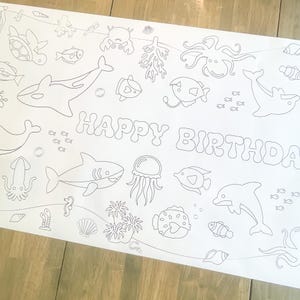 May include: A black and white colouring page featuring a variety of sea creatures, including a shark, dolphin, jellyfish, and octopus. The page also includes the words "Happy Birthday" in a whimsical font.