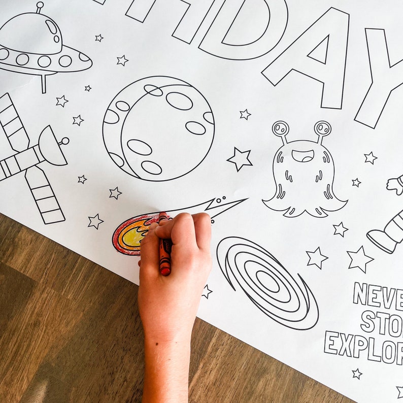 May include: A black and white coloring page with a space theme. The page features a rocket, a satellite, a planet, a comet, a galaxy, a UFO, an alien, and stars. The text "Never Stop Exploring" is at the bottom of the page.
