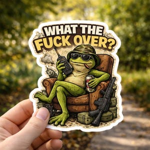 May include: A sticker featuring a cartoon frog wearing sunglasses and a hat, smoking a cigar, and holding a walkie-talkie and a can of beer. The frog is seated in a brown armchair with a rifle and ammo crates nearby. The text "WHAT THE FUCK OVER?" is at the top.