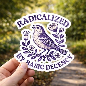 May include: A white sticker featuring a purple illustration of a bird on a branch, encircled by floral elements. The text "RADICALIZED BY BASIC DECENCY" is displayed in an arc above and below the bird.