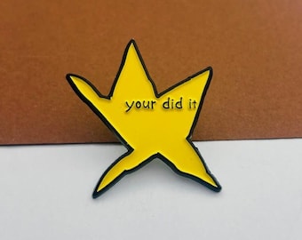 May include: A yellow star-shaped enamel pin with a black outline. The pin features the phrase "your did it" in a black, sans-serif font. The pin is set against a brown and white background.
