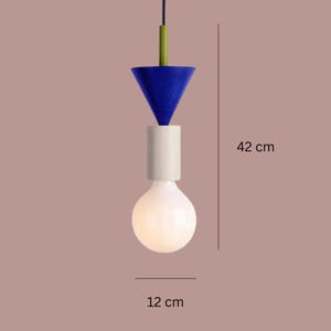 Peut inclure: Un luminaire suspendu moderne avec un design bleu, blanc et vert. L'ampoule mesure 12 cm de large et le luminaire mesure 42 cm de haut. Le luminaire a une forme de c&ocirc;ne bleu, un cylindre blanc et une ampoule blanche.