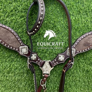 Puede incluir: Una brida de caballo de cuero marr&oacute;n con tachuelas y adornos plateados. La brida presenta una cabezada marr&oacute;n oscuro, un peto con textura similar a la piel y el texto "EQUICRAFT LEATHER AND APPAREL".