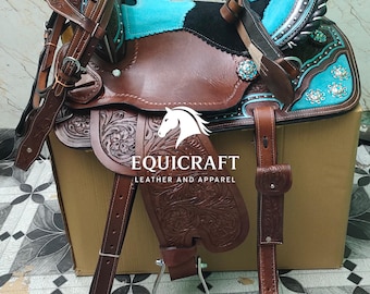 May include: A brown leather western saddle with turquoise accents and floral tooling. The saddle features a black seat, silver trim, and the text "EQUICRAFT LEATHER AND APPAREL".