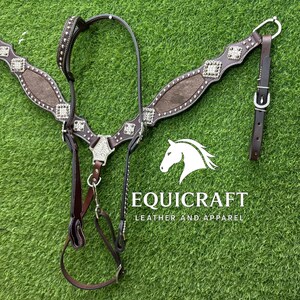 Puede incluir: Un cabezal de caballo de cuero marr&oacute;n con detalles plateados y tachuelas decorativas. El cabezal presenta una correa central para el pecho y una cabezada, con un logotipo "EQUICRAFT LEATHER AND APPAREL" en texto blanco.