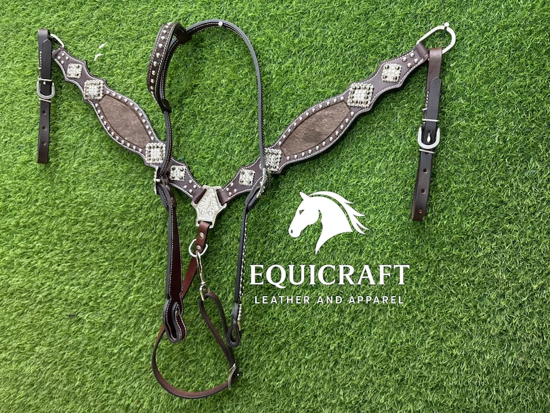 Puede incluir: Un cabezal de caballo de cuero marr&oacute;n con detalles plateados y tachuelas decorativas. El cabezal presenta una correa central para el pecho y una cabezada, con un logotipo "EQUICRAFT LEATHER AND APPAREL" en texto blanco.