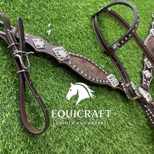 Puede incluir: Una brida de caballo de cuero marr&oacute;n con detalles plateados y pedrer&iacute;a decorativa. La brida presenta una testera y carrilleras acolchadas, con riendas a juego. La imagen tambi&eacute;n incluye el texto "EQUICRAFT LEATHER AND APPAREL".